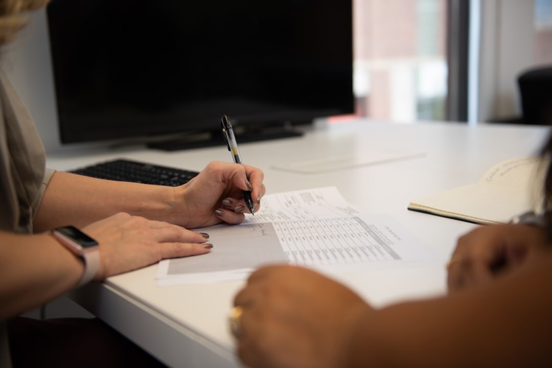 Person reading a printed document with a pen at a desk